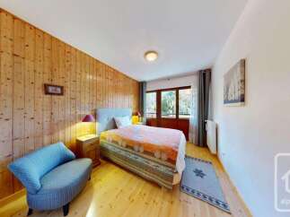 Experience cozy mountain living in this charming bedroom featuring warm wood paneling and a comfortable bed adorned with a vibrant quilt.
