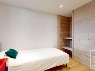 This cozy bedroom features a comfortable single bed adorned with a plush green accent pillow, perfect for relaxation.