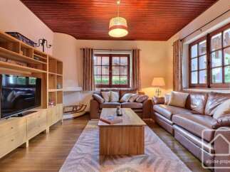 Experience cozy living in this charming living room featuring plush leather sofas and a warm wooden ceiling.