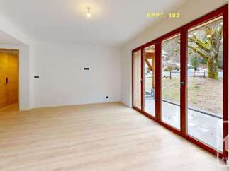 Experience modern living in this spacious apartment, featuring a bright and airy open-plan living area with large glass doors that open to a scenic outdoor view.