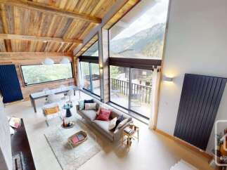 Experience luxurious mountain living in this stunning chalet, featuring a soaring vaulted ceiling with exposed wooden beams and expansive floor-to-ceiling windows that offer breathtaking panoramic views of the surrounding alpine landscape.
