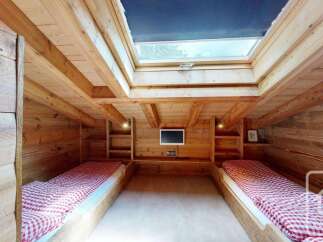Experience cozy living in this charming wooden cabin bedroom, featuring two comfortable twin beds with classic red and white gingham bedding.