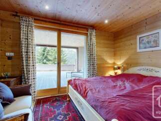 Experience luxurious mountain living in this charming bedroom featuring a plush king-sized bed with a vibrant red comforter, perfect for cozy nights.