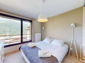 Experience breathtaking mountain views from this charming bedroom, featuring a comfortable queen-size bed adorned with crisp white linens and plush towels.