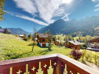 Experience the charm of alpine living in this picturesque mountain property, featuring traditional wooden chalets nestled amidst rolling green hills and majestic peaks.