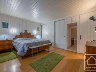 This charming bedroom features a spacious wooden bed with a decorative headboard, complemented by two bedside tables and green accent rugs.