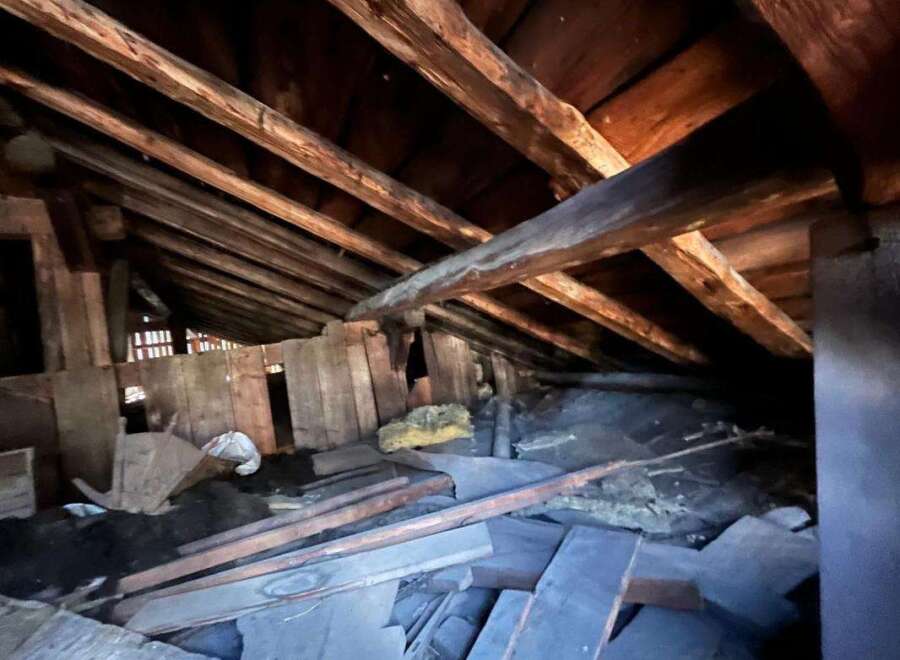 Explore the potential of this spacious attic, featuring robust wooden beams and ample room for storage or conversion.