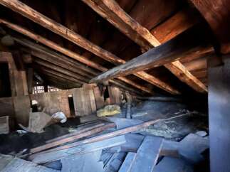Explore the potential of this spacious attic, featuring robust wooden beams and ample room for storage or conversion.