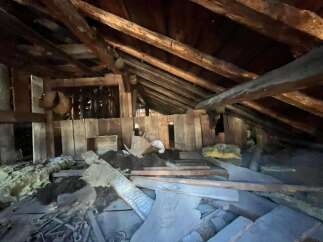 Explore the potential of this unique attic space, featuring rustic exposed wooden beams and ample room for creative renovation.