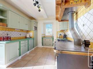 Discover this charming kitchen featuring light green cabinetry and a vibrant yellow tiled backsplash.
