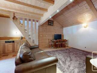 Experience cozy living in this charming alpine retreat, featuring a well-equipped kitchenette with wooden cabinetry and a spacious living area.