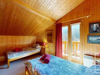 Experience cozy mountain living in this charming attic bedroom, featuring warm wood paneling throughout and two comfortable beds perfect for a family or group.