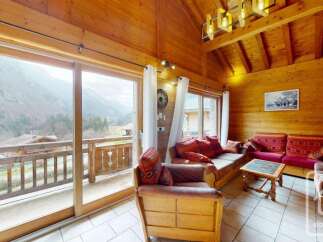 Experience breathtaking mountain views from this charming wooden living room, featuring a cozy seating area with plush cushions and a rustic coffee table.