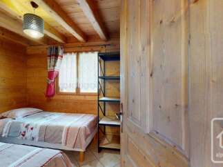 This charming wooden cabin bedroom features two comfortable twin beds with patterned bedding, perfect for a cozy retreat.