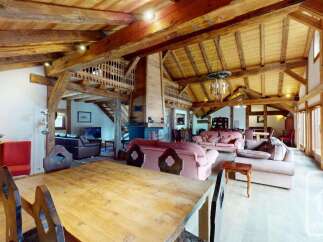 Experience rustic charm in this spacious living area, featuring exposed wooden beams and a grand stone fireplace.