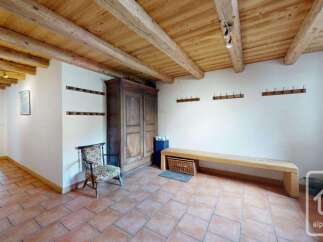 This charming entryway features rustic wooden beams on the ceiling and a warm terracotta tile floor.