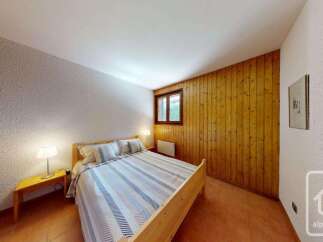 This charming bedroom features a comfortable queen-sized bed with a striped duvet and plush pillows, perfect for a restful night's sleep.