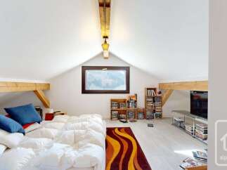 Discover this charming attic bedroom, featuring a comfortable bed piled high with plush pillows and a cozy duvet.