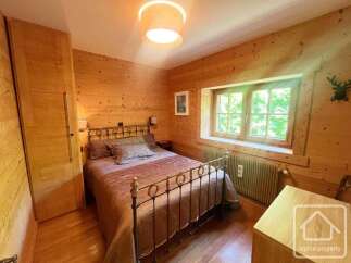 Experience rustic charm in this cozy bedroom, featuring warm wooden walls and a comfortable bed adorned with plush pillows.