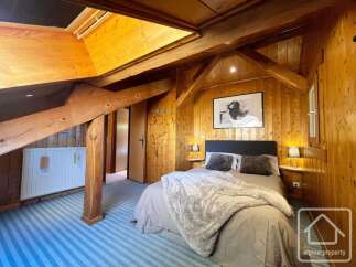 Experience cozy living in this charming wooden-paneled bedroom, featuring a comfortable bed adorned with plush pillows and a soft throw.