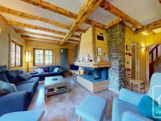 Experience rustic charm in this stunning wooden chalet living room, featuring a grand stone fireplace and exposed wooden beams.