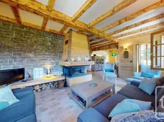 Experience rustic charm in this inviting living room, featuring a grand stone fireplace and exposed wooden beams that create a warm, cozy atmosphere.