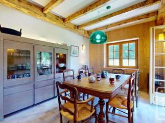Experience rustic charm in this inviting dining room, featuring exposed wooden beams and warm wood-paneled walls.