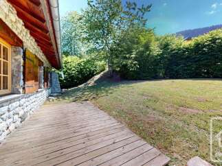 Experience the charm of this rustic property featuring a stone and wood facade, complemented by a spacious wooden deck perfect for outdoor relaxation.