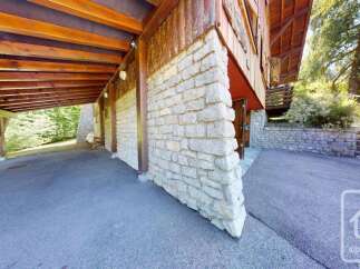 Discover this charming property featuring a rustic stone facade and a warm wooden exterior, complemented by a covered carport area.