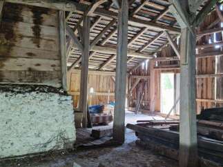 Explore the rustic charm of this traditional barn, featuring robust wooden beams and a sturdy stone foundation.