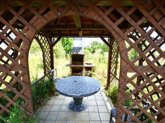 Enjoy outdoor living in this charming gazebo featuring a mosaic-topped table and a built-in brick barbecue.