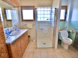 This bathroom features a spacious walk-in shower with glass doors and a tiled enclosure, perfect for a refreshing start to your day.