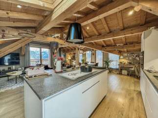 Experience breathtaking mountain views from this stunning attic apartment, featuring a modern kitchen island with granite countertops and a spacious living area.