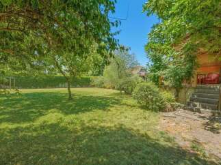 Enjoy the lush green lawn and mature trees in this spacious backyard, perfect for outdoor activities and relaxation.