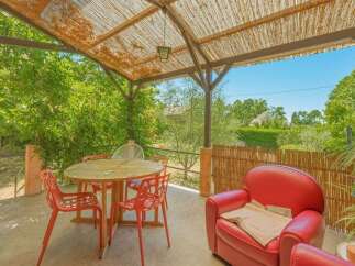 Enjoy outdoor living on this charming patio, complete with a round dining table and four vibrant red chairs, perfect for al fresco meals.