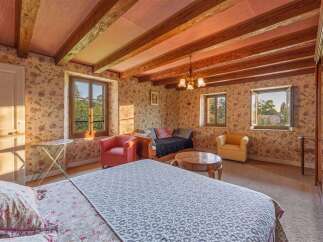 This charming bedroom features exposed wooden beams and floral wallpaper, creating a cozy and rustic ambiance.