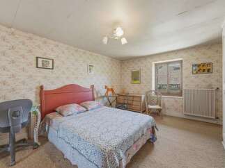 This charming bedroom features a comfortable bed with a decorative headboard, perfect for a restful night's sleep.