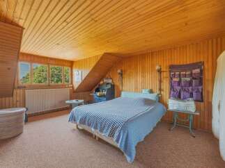This charming bedroom features a cozy atmosphere with warm wooden paneling on the walls and ceiling.