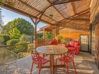 Enjoy outdoor living with this charming patio featuring a rustic thatched roof and comfortable seating.