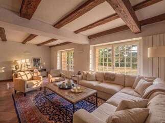 Experience rustic charm and elegant comfort in this spacious living room, featuring exposed wooden beams and a large sectional sofa perfect for gatherings.