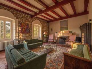 Step into this charming living room featuring exposed stone walls and rustic wooden beams, creating a warm and inviting atmosphere.
