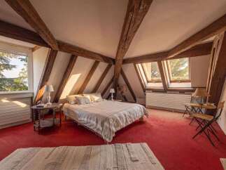 Discover this charming attic bedroom featuring exposed wooden beams and a cozy ambiance.