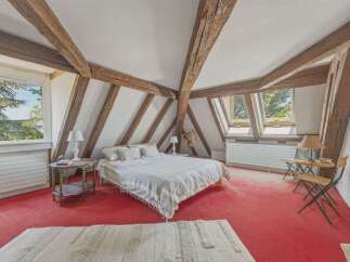 Experience rustic charm in this attic bedroom, featuring exposed wooden beams and a vaulted ceiling that adds character and warmth.