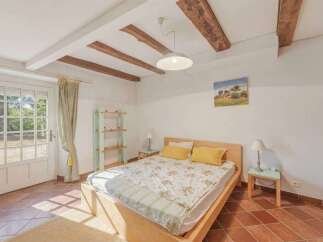 Experience rustic charm in this inviting bedroom featuring exposed wooden beams and a cozy bed adorned with a floral comforter.