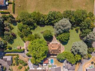 Discover this stunning property from an aerial perspective, showcasing a spacious home nestled amidst lush greenery and mature trees.