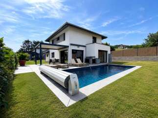 Experience luxurious outdoor living with this stunning modern home featuring a sparkling blue swimming pool and a sleek automatic pool cover.