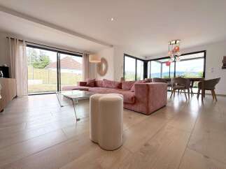 Experience modern living in this spacious open-plan lounge and dining area, featuring a plush pink sectional sofa and a stylish glass coffee table.