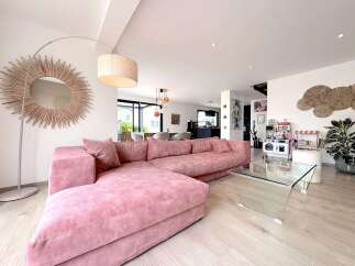 Experience modern living in this spacious open-plan home, featuring a plush pink sectional sofa perfect for relaxation.