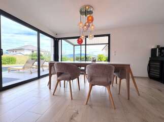 Experience modern living in this stunning dining area, featuring expansive sliding glass doors that seamlessly connect to an outdoor oasis with a pool and lounge chairs.