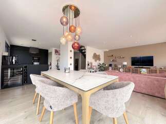 Experience modern living in this open-concept home featuring a sleek black kitchen with integrated appliances and a stylish wine cooler.